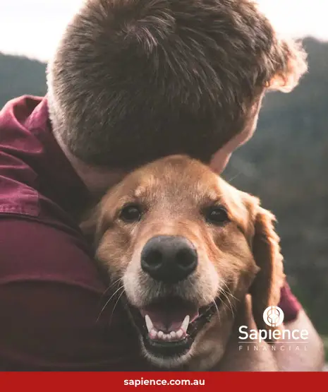 man hugging his dog outside in the mountains