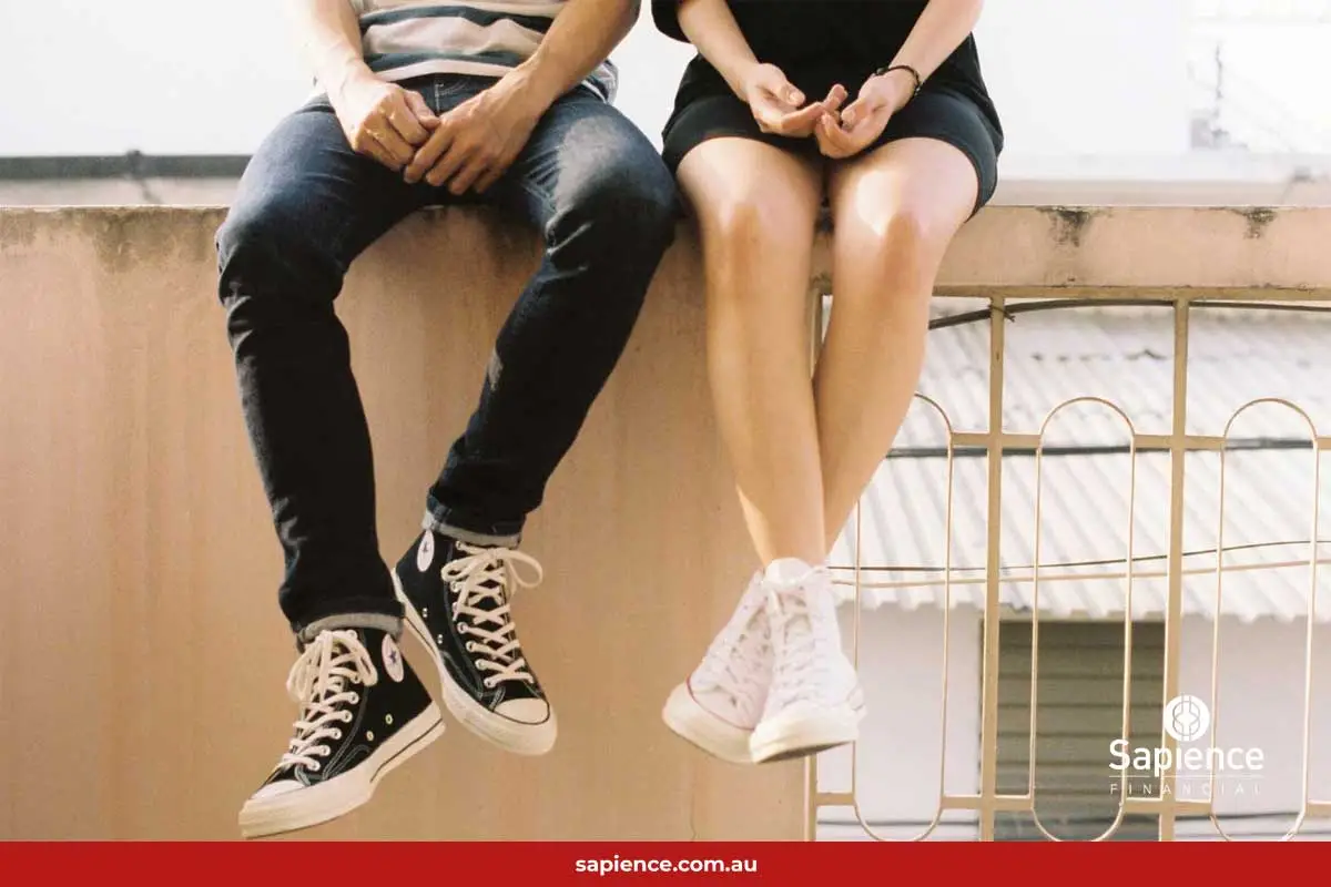 legs of couple sitting on fence