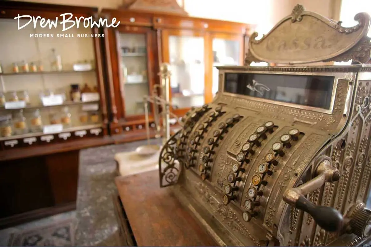A close up image of a metal traditional crank driven golden metal cash register at an old time country store